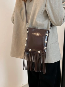 Dark brown patent leather bucket bag with silver studs and long tassels on a crossbody strap