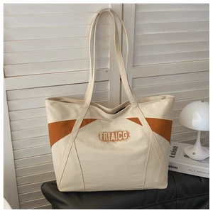 Detail view of a large canvas tote bag with orange contrast trim and letter printing