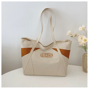 Detailed shot of canvas tote bag with contrast brown trim and letters on a table