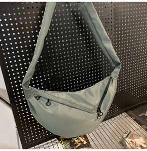 Detail of sage green dumpling bag with zipper pocket and wide adjustable strap