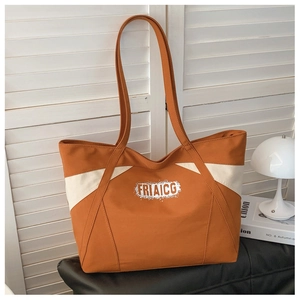 Detail of large canvas tote bag showing the orange color block design and logo