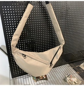 Detail view of beige crescent bag with wide shoulder strap and waterproof nylon texture
