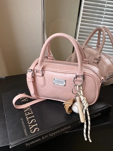 Pink glossy bowling bag with baseball charm on books with mirror reflection