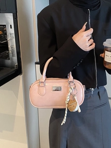 Pink faux leather boston handbag with strawberry charm and top handles in use
