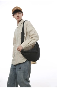 Detail of black nylon crescent crossbody bag featuring an adjustable strap and zip closure
