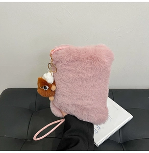 Detailed macro shot of pink faux fur texture and cute plush monster charm on small bag