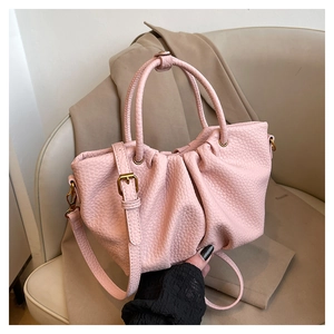 Détail du sac seau rose plissé montrant le cuir litchi et les garnitures dorées