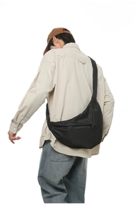 Ergonomic black crescent crossbody bag with adjustable strap shown on a model