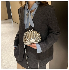 Detail of silver shell-shaped clutch with acrylic chain strap and pearl edge decoration