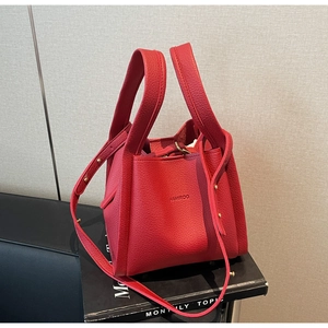 Macro shot of red pebble leather bucket bag with embossed logo and wide handles