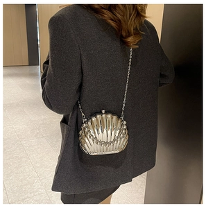 Detail of silver shell-shaped evening bag with pearl chain shown on model's shoulder