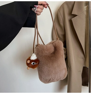 Detailed close-up of dark brown plush crossbody bag with a cute monster pendant charm
