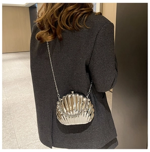 Detailed back view of a silver shell-shaped bag with acrylic chain on a grey blazer