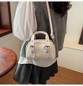 Détail du sac Boston en similicuir blanc cassé avec boucles argentées et bandoulière