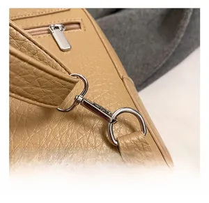 Detail of silver metal hook and zipper on beige lychee texture leather backpack
