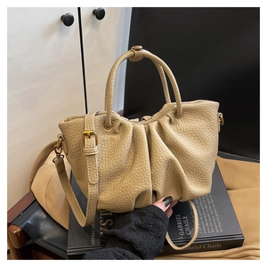Détail du sac seau plissé beige présentant une texture grainée et des boucles dorées