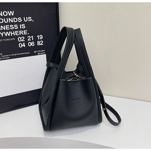 Detailed macro view of black litchi grain leather texture and embossed logo on bucket bag