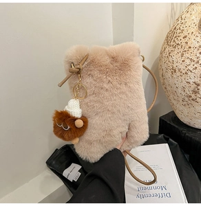 Close-up of beige plush crossbody bag featuring a cute brown bear charm and gold hardware