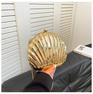 Detail of a golden shell evening clutch with high-gloss polish and metal chain strap