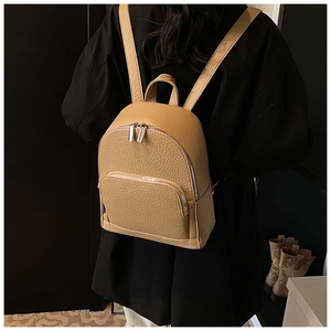 Close-up of khaki pebbled leather backpack showing metal zipper and handle texture