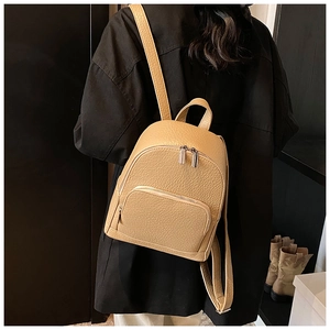 Close-up of beige lychee texture leather backpack showing front pocket and silver zipper detail