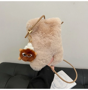 Detail of beige plush crossbody bag with soft faux fur texture and a cute charm