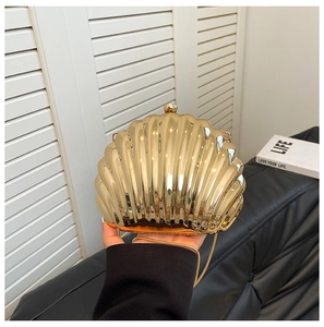 Macro detail of golden seashell mini bag featuring mirror finish and metallic ball clasp