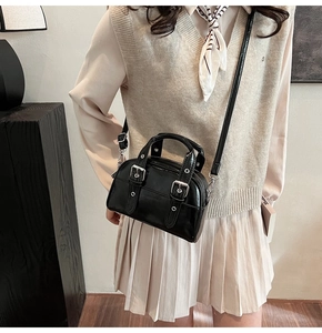Détail du mini sac vintage en cuir verni noir avec doubles sangles rétro et œillets métalliques