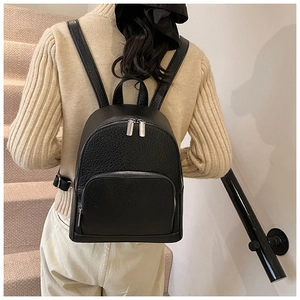 Rear view of model wearing a black lychee-textured leather backpack on a staircase
