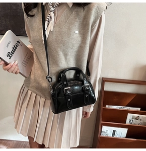 Détail d'un petit sac à main noir brillant avec boucles argentées et bandoulière amovible