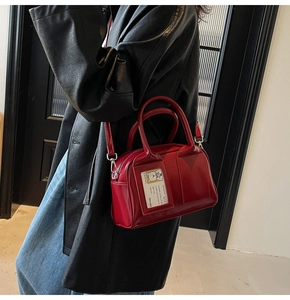 Detail view of a bright red glossy Boston bag with a cartoon bear card slot on person