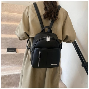 Rear view of a model wearing the black pebbled leather backpack with silver zippers
