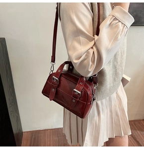 Détail du sac bandoulière en cuir verni bordeaux avec sangles et boucles argentées