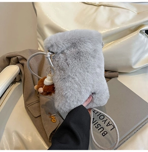 Detail of grey fluffy crossbody bag showing soft texture and bear charm accessory