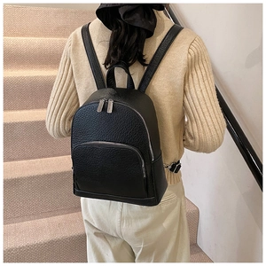 Close-up of black lychee grain leather backpack with silver metal zippers on model