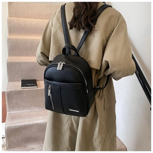 Close-up of black pebble leather backpack for women with silver metal zippers on a model