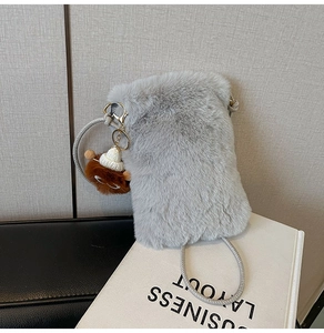 Close-up of grey faux fur crossbody bag featuring a cute plush doll charm and rope strap