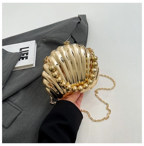Detailed view of the gold shell-shaped evening clutch with polished metallic finish and chain