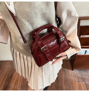 Détail d'un sac à main bordeaux brillant en cuir verni avec une bandoulière réglable