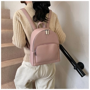 Close-up of pink litchi grain leather backpack worn on shoulder at stairs
