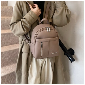 Detail of taupe pebbled leather mini backpack with silver zippers and metal logo plate