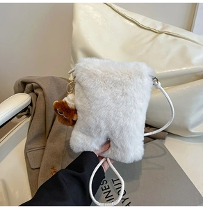 Detail of white faux fur crossbody bag with cute brown teddy bear charm and slim strap