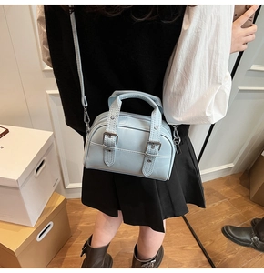 Détail d'un mini sac Boston bleu clair porté en bandoulière par un mannequin