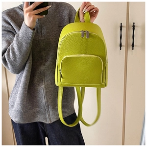 Detail of a bright green mini PU leather backpack with a pebbled texture and silver zippers