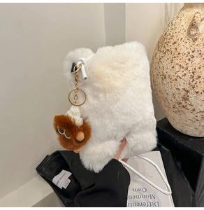 Close-up of plush cream faux fur crossbody bag with a cute brown monster charm detail