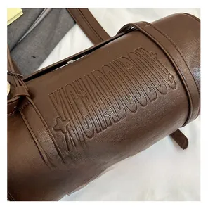 Detail shot of vintage brown barrel bag with embossed letter logo and star patterns