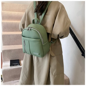 Close-up of light green pebble leather backpack with side zipper pocket on a model