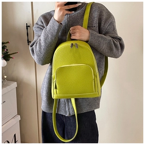 Mirror selfie showing a mini lime green lychee grain leather backpack on a shoulder