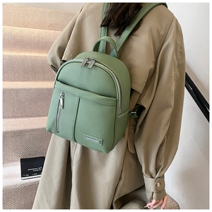 Close-up of grass green litchi grain leather backpack with sleek metal logo detail