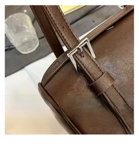 Detail of silver buckle and adjustable shoulder strap on dark brown leather bag